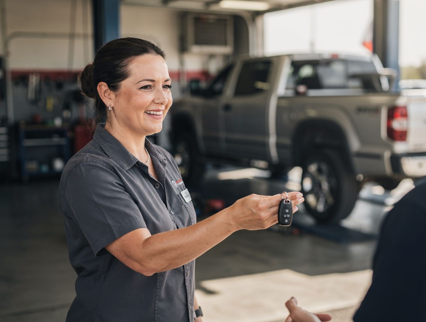 A service advisor handing keys back to a customer in a dealership service lane.
